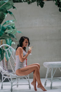 Young woman using mobile phone while sitting on chair
