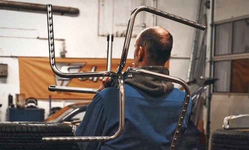 Rear view of mechanic holding chassis in workshop