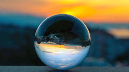 Close-up of crystal ball on sea during sunset