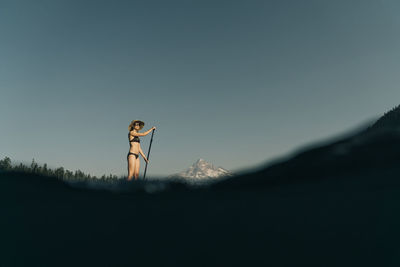 A young woman enjoys a standup paddle board on lost lake in oregon.