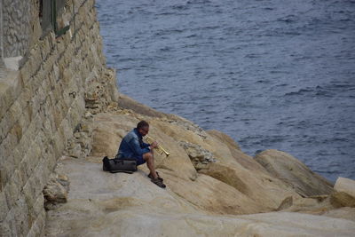 Man sitting on rock by sea