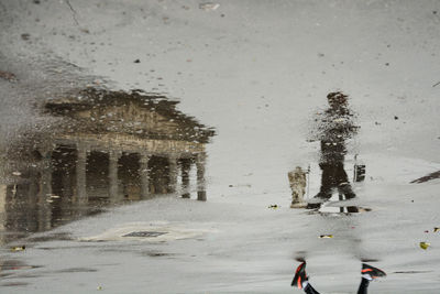 Man walking on wet street during winter