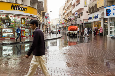 Man walking on wet street in city during rainy season