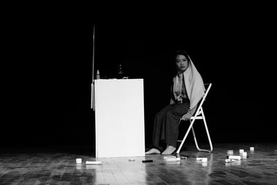 Woman sitting on chair in darkroom
