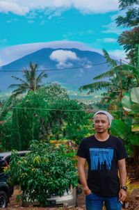 Portrait of smiling young man standing against plants