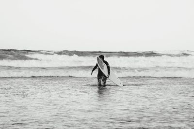 Full length of man standing in sea against clear sky