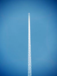 Low angle view of vapor trails against clear blue sky