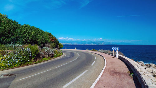 Road by sea against blue sky