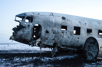 Abandoned airplane at beach against sky during winter