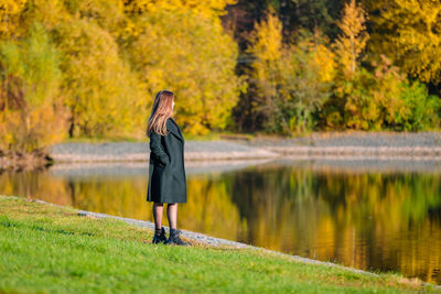 A woman with long hair walks in an autumn park by the pond. autumn season. person