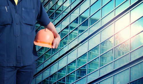 Midsection of engineer standing against building during sunset