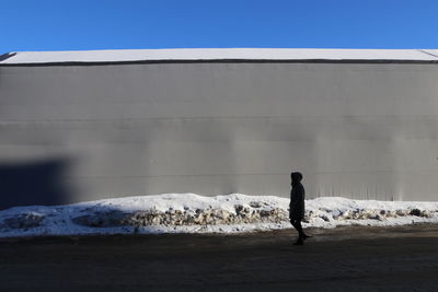 Rear view of man walking on snow covered land