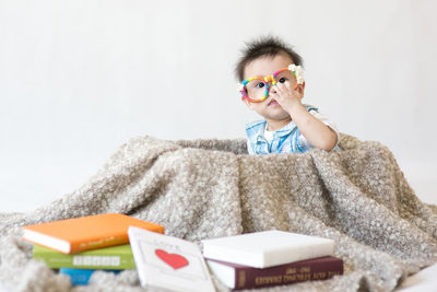 Portrait of cute boy sitting by books at home