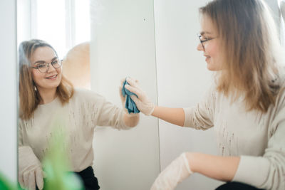 Positive woman cleaning glass at home