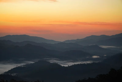 Scenic view of silhouette mountains against orange sky