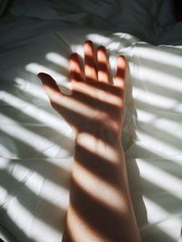 Close-up of human hand on bed