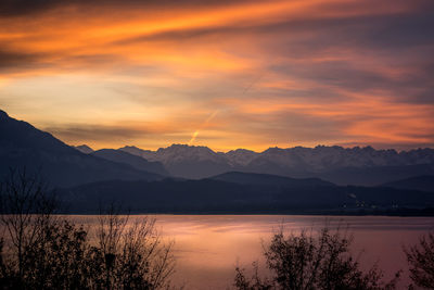 Scenic view of lake and mountains against orange sky