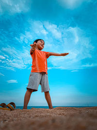 Full length of woman standing on beach against blue sky