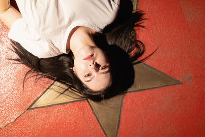 High angle portrait of woman lying down on floor