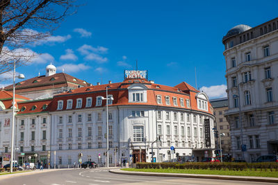 Road by buildings in city against sky