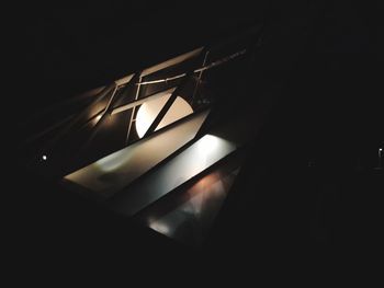 Low angle view of illuminated light bulb in darkroom