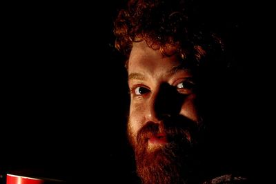 Close-up portrait of man against black background