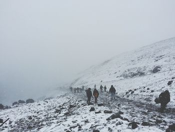 People on snow covered landscape against sky