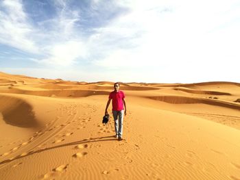 Rear view of woman standing on sand dune