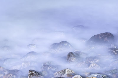 Close-up of snow on rocks against sky