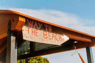 Low angle view of text on wood against sky