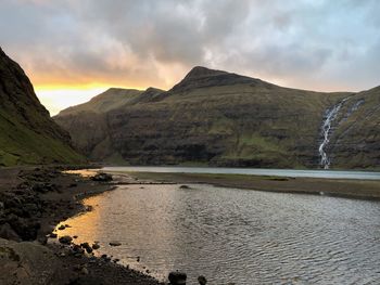 Scenic view of lake by mountains against sky during sunset