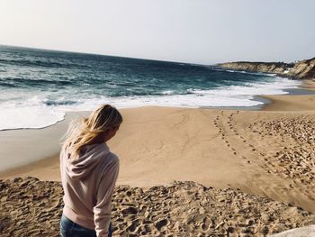 Rear view of woman standing at beach