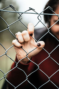 Close-up of hand holding chainlink fence