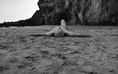 Monochrome of shirtless adult man lying on beach