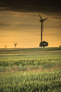 Windmill on field against sky during sunset
