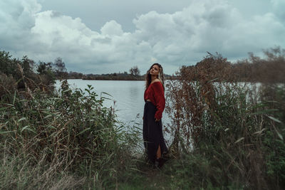 Woman standing by lake against sky