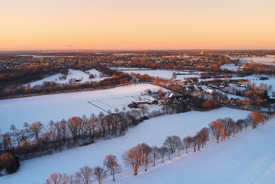 Drone view of landscape and fields in germany covered with snow during sunset