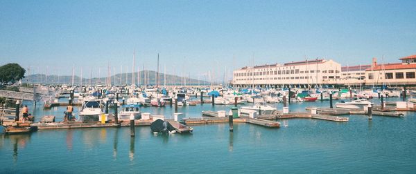 Boats moored in harbor against buildings in city