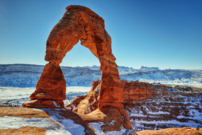 Rock formation in sea against clear blue sky