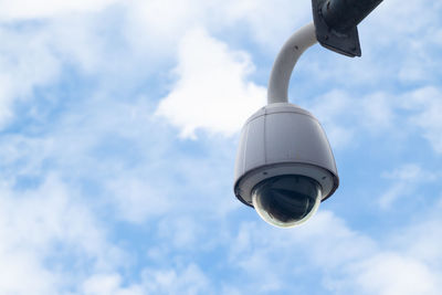 Low angle view of security camera against cloudy sky