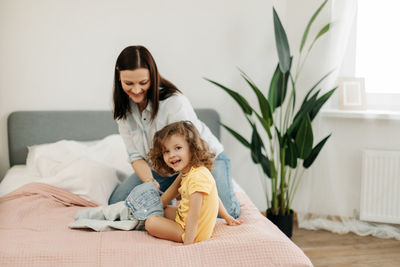 A young mother helps her little daughter to change clothes. taking care of children, help