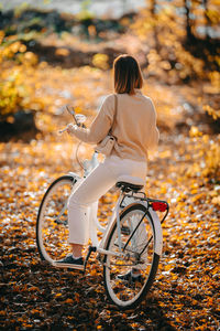 Rear view of woman with bicycle during autumn