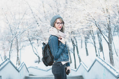 Side view portrait of young woman with bag wearing warm clothing during winter