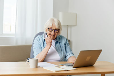 Young woman using laptop while sitting on table at home