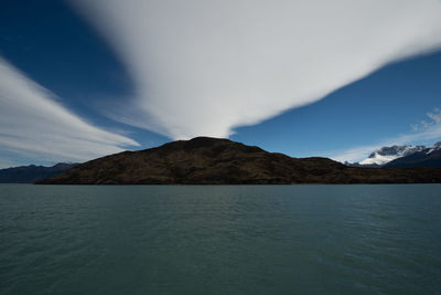 Scenic view of sea by mountains against sky