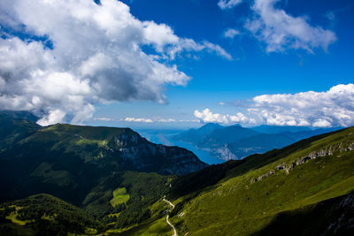 View of lake garda between rocks, clouds and blue sky on monte altissimo di nago in trento, italy