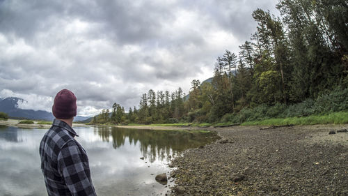 Rear view of woman standing by lake against sky