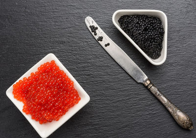 Grainy caviar of paddlefish fish in a white ceramic plate and red chum salmon caviar in a whit