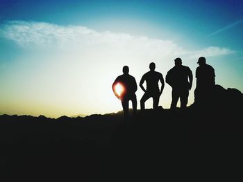 Silhouette men standing on mountain against sky during sunset