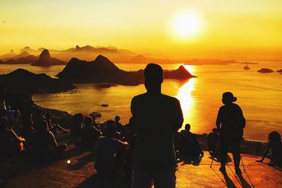 Silhouette of tourists contemplating on hill during sunset